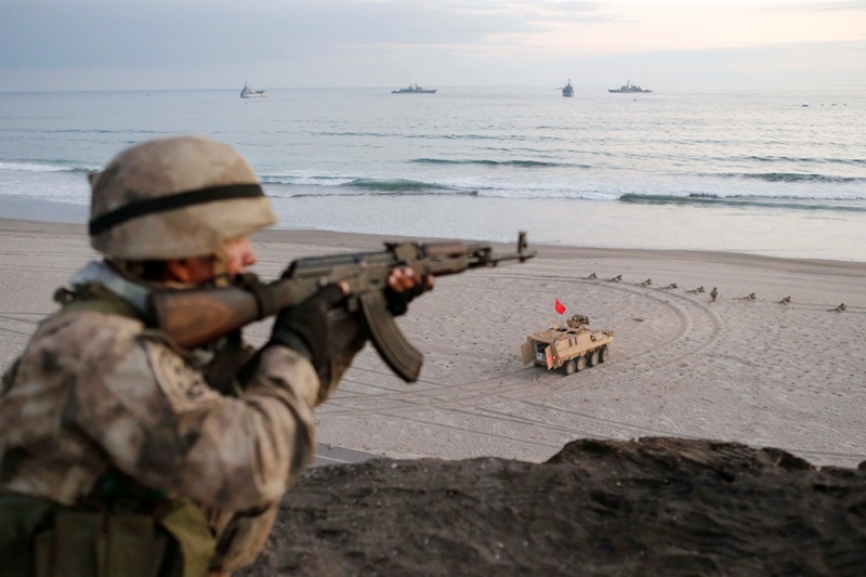 Infante de Marina armado con un AKM de 7.62x39 mm. En la playa se observa un Vehículo Blindado GDLS LAV-II (8x8) Caimán.(Ministerio de Defensa del Perú)