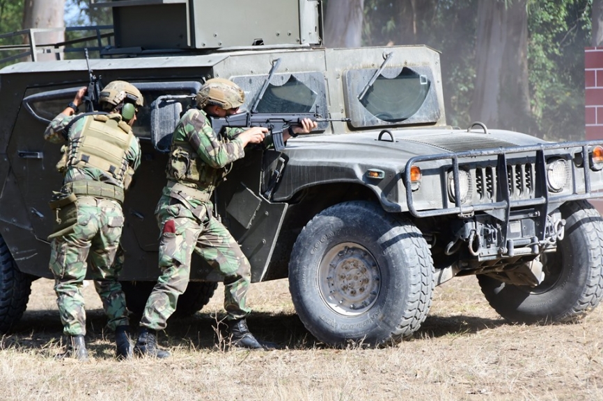 Un “Comando”, como denota la boina roja que lleva en el bolsillo del pantalón, apunta su SCAR-L apoyado en el capo de un 4x4 Hummer.