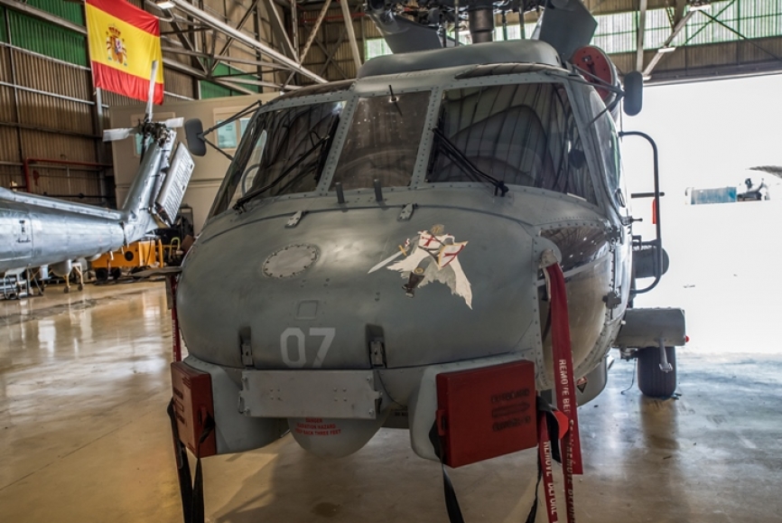 Un precioso templario adorna el “morro” (bahía de equipamiento de aeroelectrónica) de este SH-60B. Abajo se encuentran unos cuadrados de color rojo, son las cubiertas de las antenas delanteras. Lo que parece una pequeña antena en la parte superior del cristal rectangular de la cabina, es el indicador de temperatura del aire exterior, y en la parte inferior de dicho cristal, los dos pequeños pivotes cilíndricos que se aprecian, son las sondas de información aérea. A la izquierda del “morro” y cubierta con una funda de color marrón, se sitúa la válvula del extremo interior del indicador de velocidad.