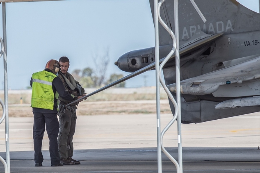 El piloto ya se encuentra preparado para subirse al avión y recibe las últimas indicaciones. Como no podría ser de otra manera, la relación y confianza entre piloto y equipo es absoluta. Se aprecia en la imagen una protuberancia en la parte posterior del alerón trasero, en ella se encuentran la válvula de aire a reacción del control de aspas, toberas de babor y estribor, antenas RWR traseras y tobera trasera de aire a reacción del control de inclinación.
