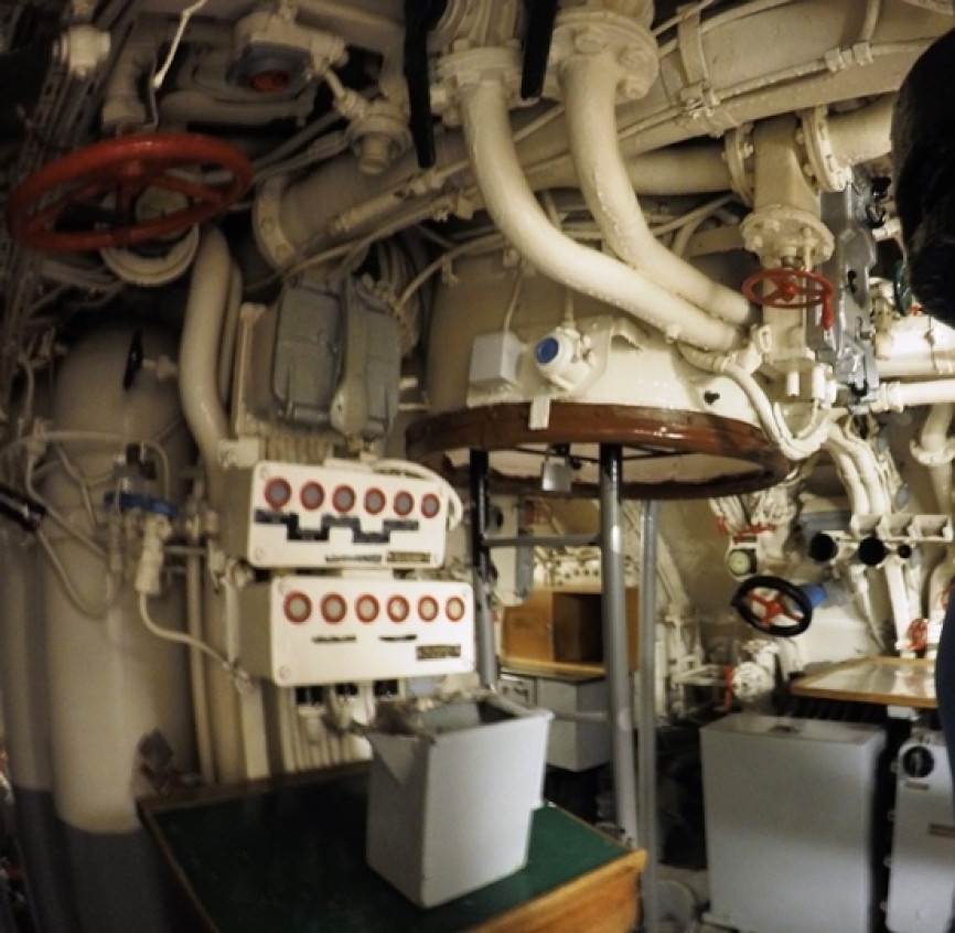 Sala de control (puente de mando). En el centro de la imagen se aprecia la escalera que conduce a la escotilla principal (que conduce a la torre, donde se ubicaban los vigías durante las patrullas) y al puesto de control de disparo, desde donde el capitán calculaba la solución de disparo cuando el submarino atacaba sumergido.