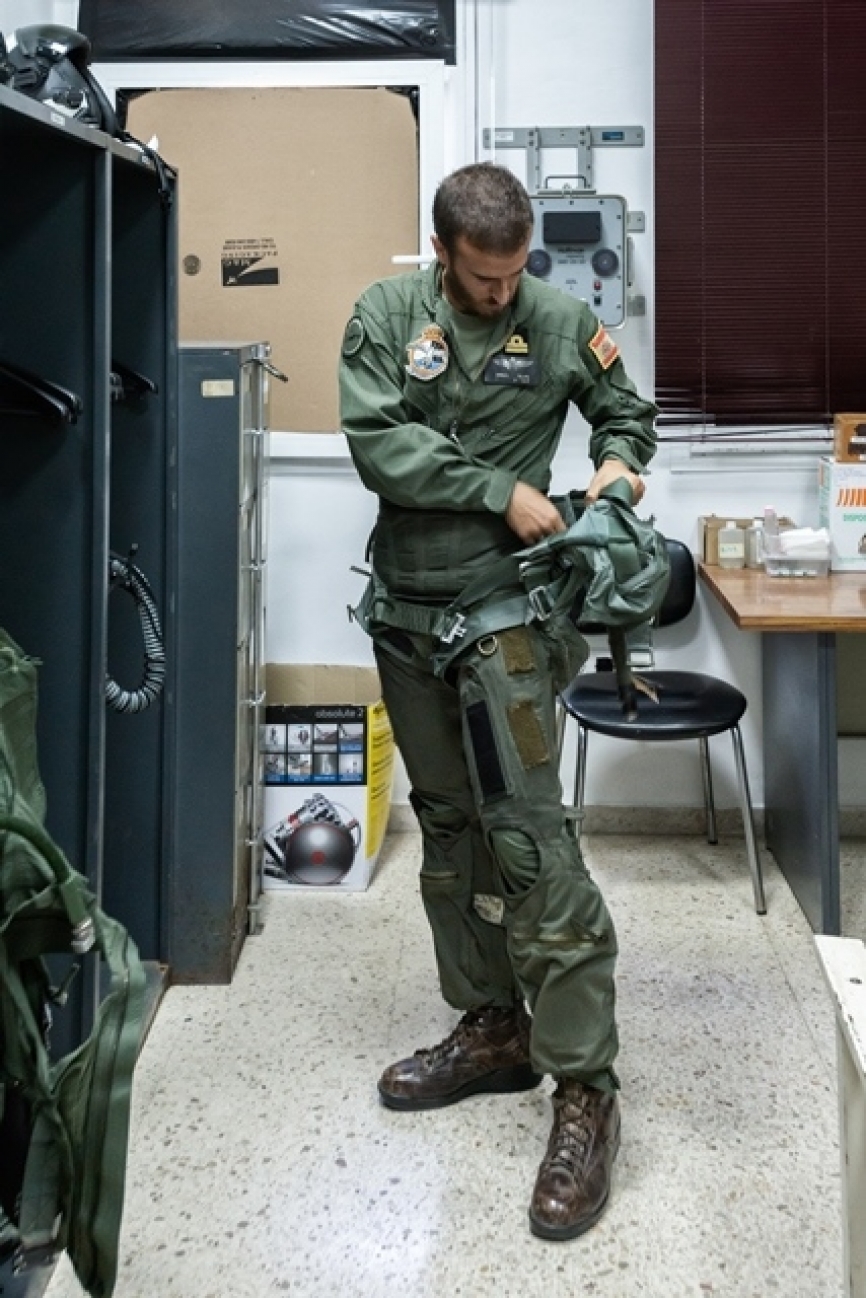 En esta imagen, el piloto ya ajustó el CSU-13P y comienza a colocarse el arnés modelo CPU-33.