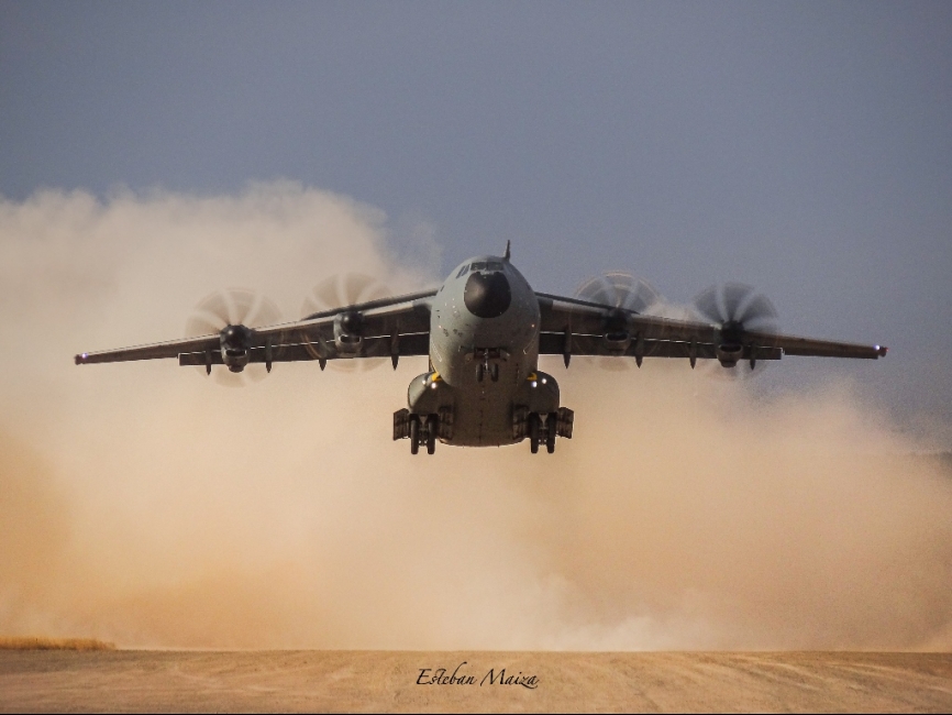 Un A-400M despegando de una pista de tierra dejando una nube de polvo a su paso.