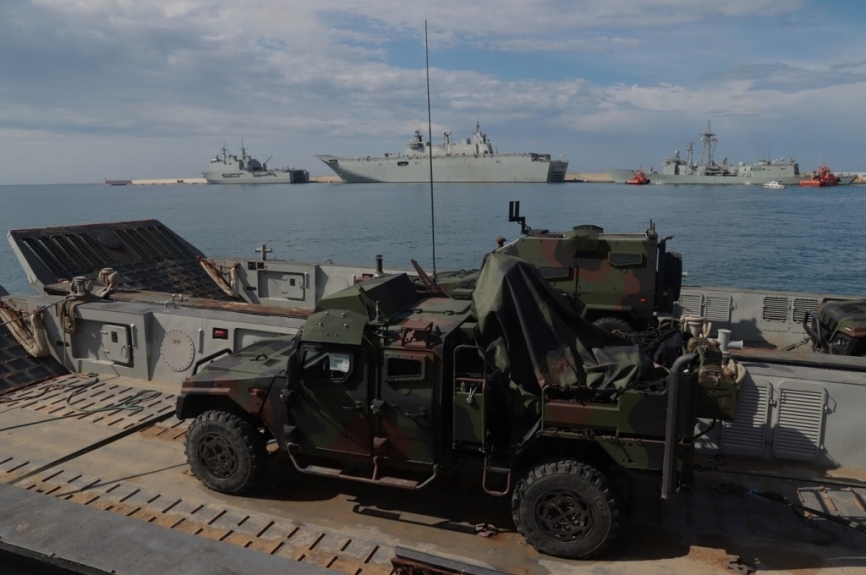 Un EIMOS estibado en una LCM-1E, al fondo se ven los navíos de asalto anfibios “Castilla” (izquierda) y el “Juan Carlos I”, que les pueden proyectar a cualquier lugar del mundo. (foto Julio Maíz)