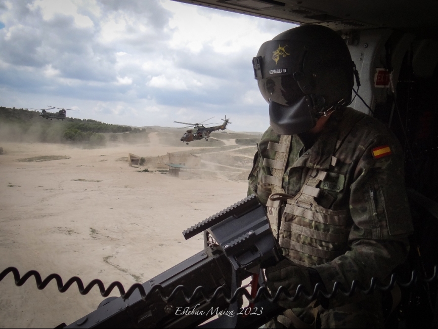 Un tirador de ametralladora M3M del BHELMA III con un ‘Cougar’ español y un ‘Chinook’ británico despegando de fondo.