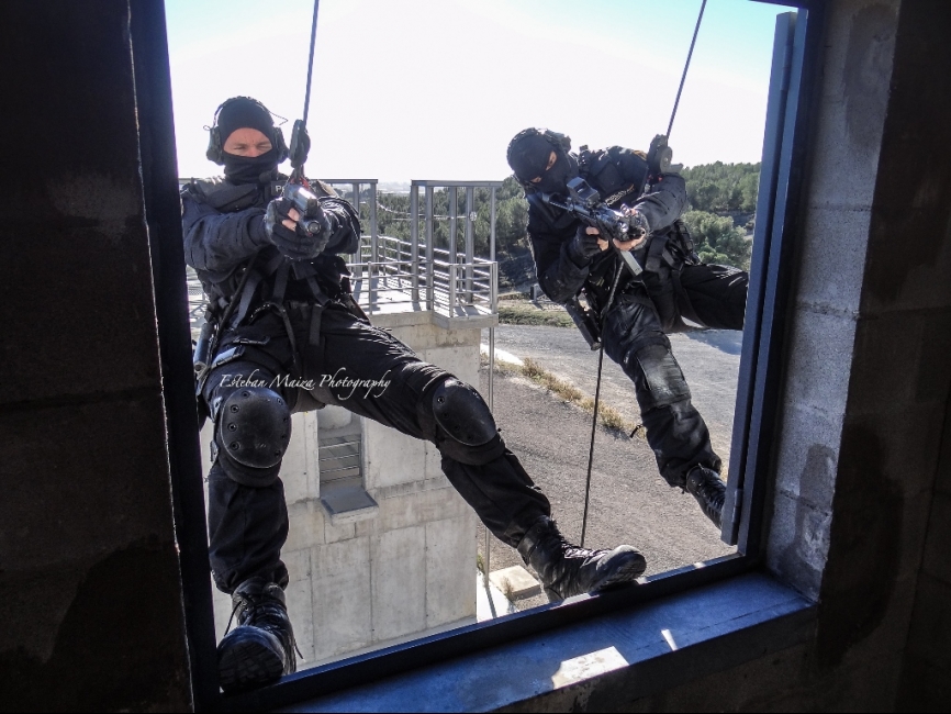 Dos operadores ejecutando una entrada en una por fachada en una habitación tras haber descendido de la azotea mediante rappel.