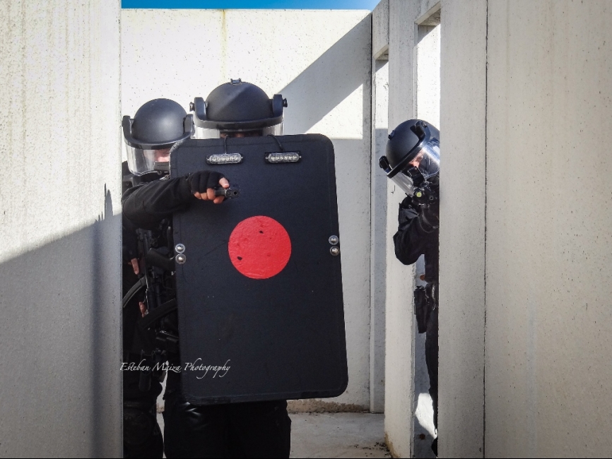 Un equipo de asalto avanzando con el escudo de protección balística al frente por un pasillo.